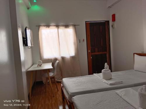 a bedroom with two beds and a desk and a window at RSK Beach and Accommodation in Dapa