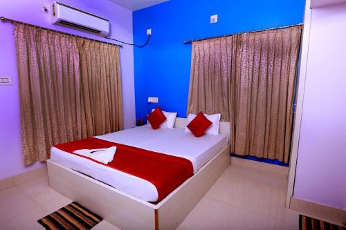 a bedroom with a bed with blue walls and red pillows at Railview inn Bhubaneswar in Bhubaneshwar