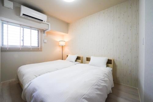 2 weiße Betten in einem Zimmer mit Fenster in der Unterkunft Branchera Naha 1102 in Naha