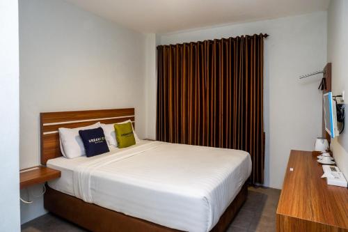 a bedroom with a large white bed and a desk at Urbanview Hotel Nostos Wonosobo by RedDoorz in Ngasinan