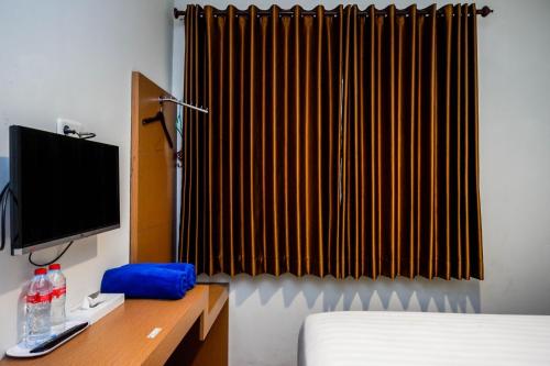 a bedroom with a bed and a monitor and a television at Urbanview Hotel Nostos Wonosobo by RedDoorz in Ngasinan