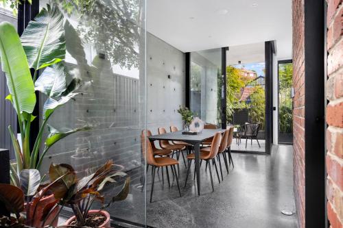 a dining room with a table and chairs and plants at The Arc Bondi Beach in Sydney