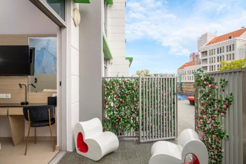 a balcony with white chairs and a fence with flowers at ibis Styles Singapore Albert in Singapore