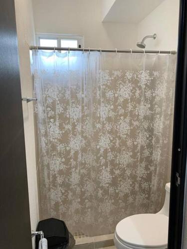 a bathroom with a shower curtain with a toilet at Hermoso apartamento piscina, céntrico, área libre. in Cancún