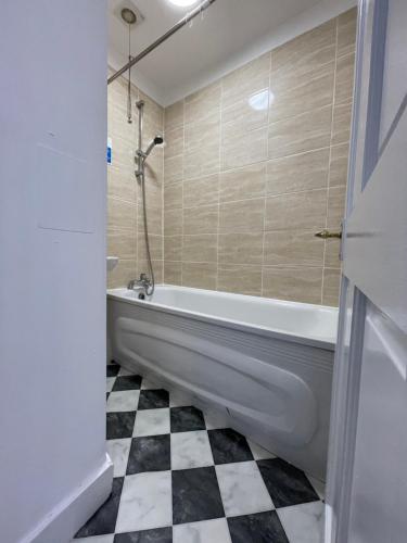 een badkamer met een bad en een zwart-wit geruite vloer bij Miles building 2 in Londen