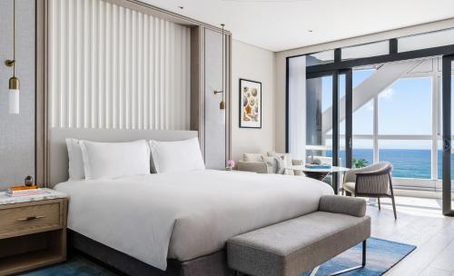 a bedroom with a large white bed and a chair at The Langham, Gold Coast and Jewel Residences in Gold Coast