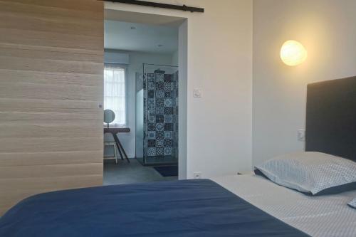 um quarto com uma cama azul e um espelho em Rhun Izella - Maison avec vue exceptionnelle - Jacuzzi et Sauna face à la mer em Plougasnou