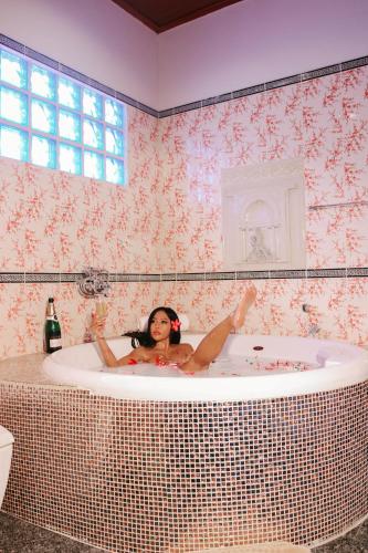 a woman laying in a bath tub in a bathroom at Namphung Phuket Boutique Resort in Rawai Beach