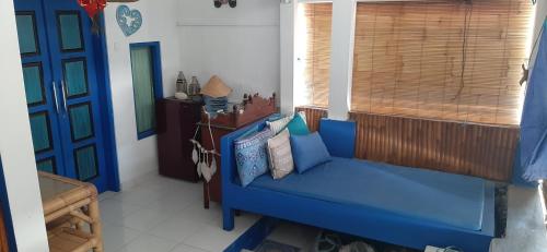 een blauwe bank in een kamer met een raam bij Isin Gumi Homestay in Amed