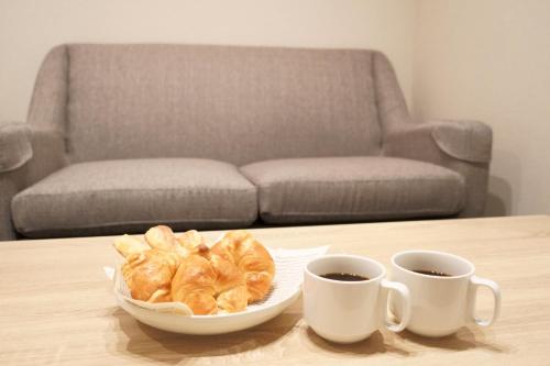 a bowl of croissants and two cups of coffee on a table at Koti Sopo Universal Bay 4 by Liaison in Osaka