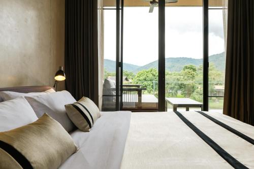 a bedroom with a large bed with a large window at Atta Lakeside Resort Suite - SHA Plus Certified in Mu Si