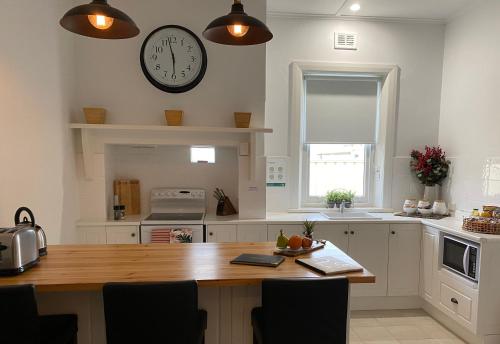 a kitchen with a wooden table and a clock on the wall at Two Cow Cottage Bed & Breakfast in Keith