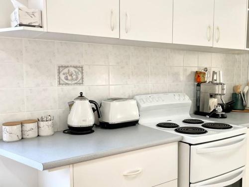 a kitchen counter with a stove and a tea kettle at Beautiful 4-bedroom original beach cottage in Port Kembla in Port Kembla