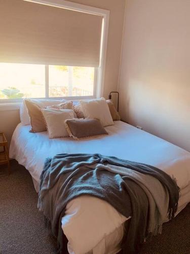 a bedroom with a large white bed with a window at Beautiful 4-bedroom original beach cottage in Port Kembla in Port Kembla