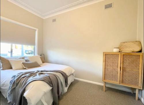 a bedroom with a bed and a window at Beautiful 4-bedroom original beach cottage in Port Kembla in Port Kembla