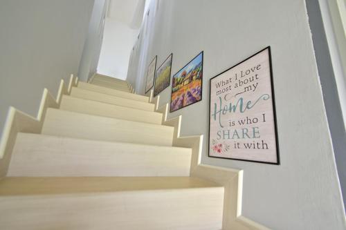 a stairwell with white stairs with pictures on the wall at D'Ja Smoke Homestay in Kampong Wakaf Tengah