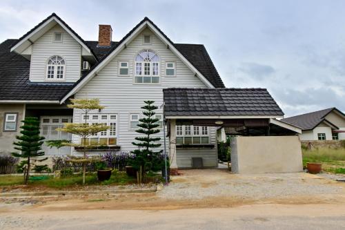a large white house with a garage at D'Ja Smoke Homestay in Kampong Wakaf Tengah