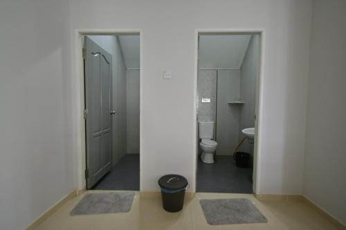 a bathroom with a toilet and a doorway with a trash can at D'Ja Smoke Homestay in Kampong Wakaf Tengah