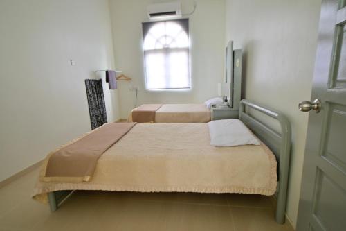 two beds in a room with a window at D'Ja Smoke Homestay in Kampong Wakaf Tengah