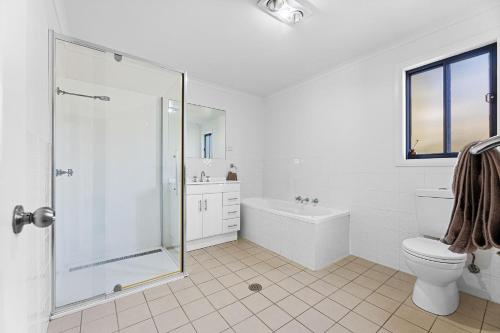 ein weißes Bad mit einer Dusche und einem WC in der Unterkunft Blue Haven in Kianga