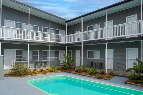 a building with a swimming pool in front of a building at Pacific Motel 11 in Forster
