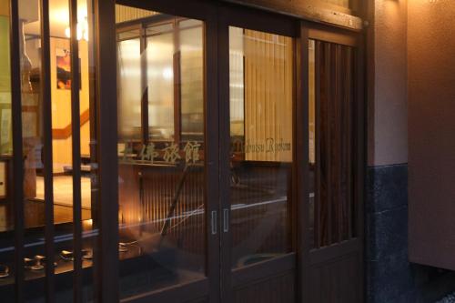 a glass door of a building with a reflection in it at Daibutsu Ryokan in Takaoka