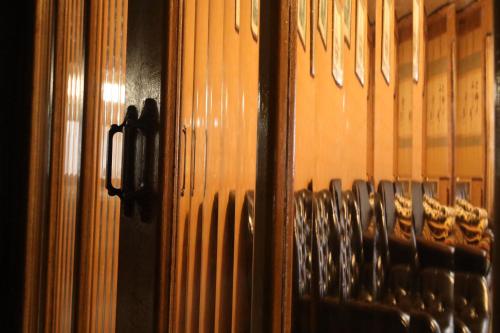a wooden wall with a rack of wine glasses at Daibutsu Ryokan in Takaoka