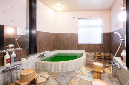 baño grande con bañera y piscina verde en Daibutsu Ryokan, en Takaoka