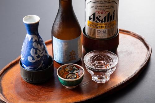 a wooden tray with two bottles and a glass of water at Daibutsu Ryokan in Takaoka