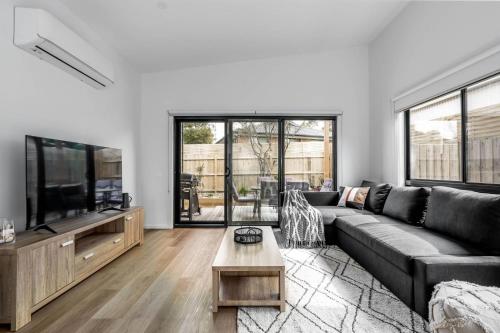 a living room with a couch and a flat screen tv at The House with the Orange Door, Inverloch in Inverloch