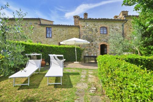 a house with two lawn chairs and an umbrella at Pozzovecchio - Happy Rentals in Casole dʼElsa