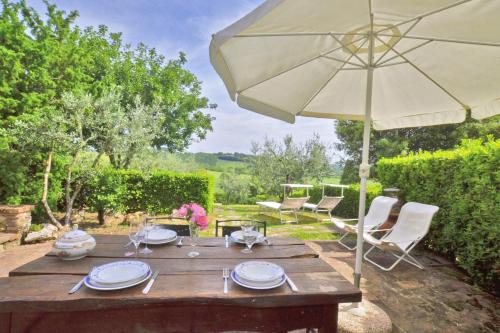 a wooden table with an umbrella and chairs at Pozzovecchio - Happy Rentals in Casole dʼElsa