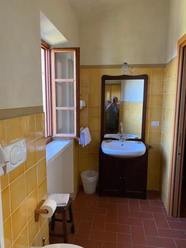 un hombre tomando una foto de un baño con lavabo en Agriturismo Montecchio, en Semproniano