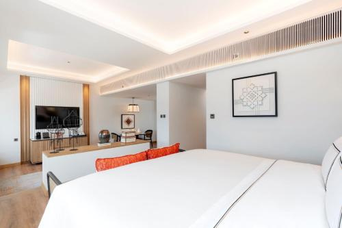 a bedroom with a white bed and a living room at Melia Chiang Mai in Chiang Mai