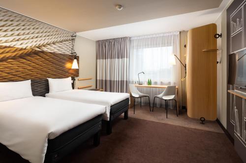 um quarto de hotel com duas camas e uma mesa em Ibis Poznan Centrum em Poznań