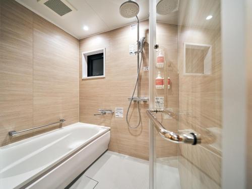 een badkamer met een douche en een wit bad bij Rakuten STAY Naha-Miebashi Suite Room in Naha