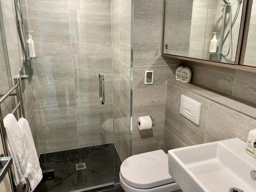 een badkamer met een douche, een toilet en een wastafel bij Garden Apartment in Queenstown