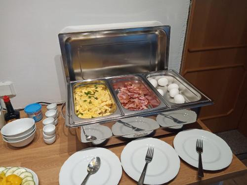 a tray of food on a table with plates and forks at ApartOne Land-Hotel in Sebnitz
