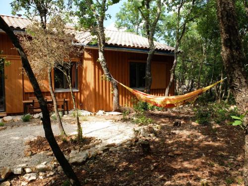 a hammock in front of a house in the woods at Gite et cabane écologiques 1000 Pailles in Labastide-de-Virac