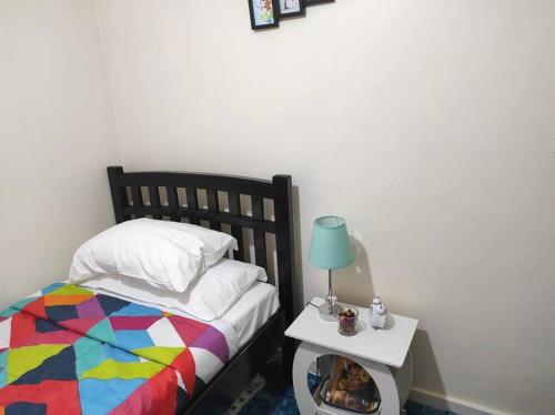 a bedroom with a bed with a colorful comforter and a side table at Walk to Strathmore Uni, Java, Wilson Airport,tmall in Nairobi