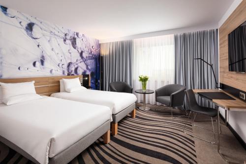 a hotel room with two beds and a desk at Novotel Poznan Centrum in Poznań