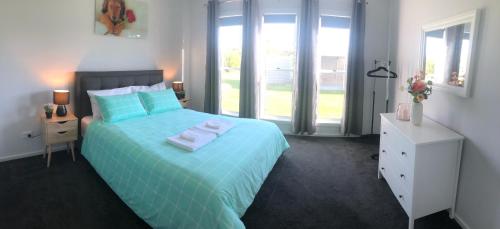a bedroom with a blue bed with towels on it at CandE on Samphire in Kingscote