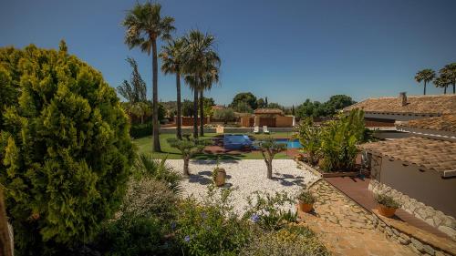 un patio trasero con piscina, palmeras y una casa en Hotel Boutique Canelobre, en Busot