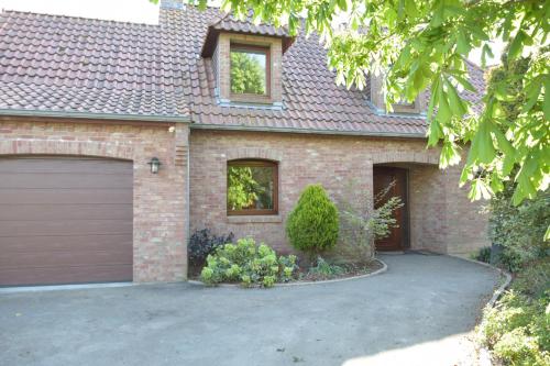 une maison en briques avec un garage et une allée dans l'établissement Les chambres du Vert Galant Rez de jardin, à Verlinghem