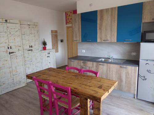 a kitchen with a wooden table and pink chairs at AltaValle Holiday Home, monolocale Pink e bilocale Lime in Chiesa in Valmalenco