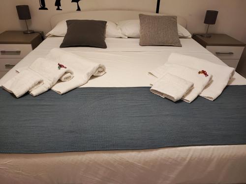 Una cama blanca con toallas y almohadas. en mungiBEDdu Apartment en Catania