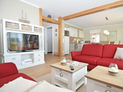 ein Wohnzimmer mit roten Sofas und einem TV in der Unterkunft Haus Mönchgut - Haushälfte 2 "Findling" in Alt Reddevitz