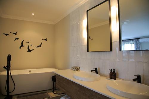 een badkamer met 2 wastafels, een spiegel en een bad bij Simbavati Fynbos on Sea Cottage in Sedgefield