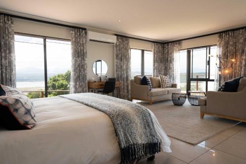 a bedroom with a large white bed and windows at Simbavati Fynbos on Sea Cottage in Sedgefield