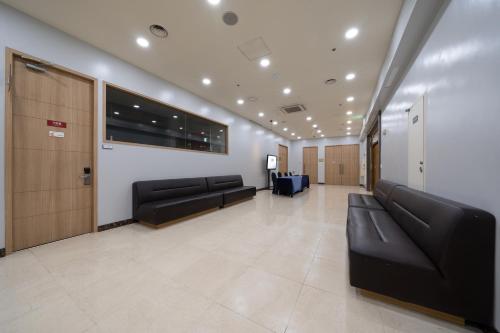 a waiting room with black leather couches in a building at Ramada by Wyndham Seoul Dongdaemun in Seoul